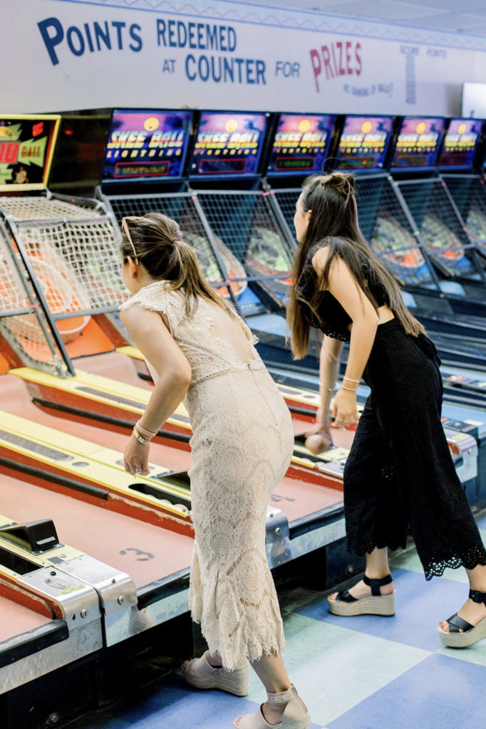 2 women playing arcade games together in coordinating dresses