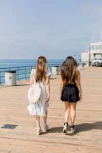 2 women walking together and having a good time on a pier