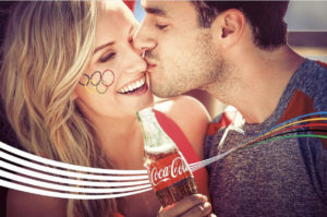 Man kissing woman who's holding a coca-cola for the Why Coke Makes Us Think #ThatsGold campaign for the olympics