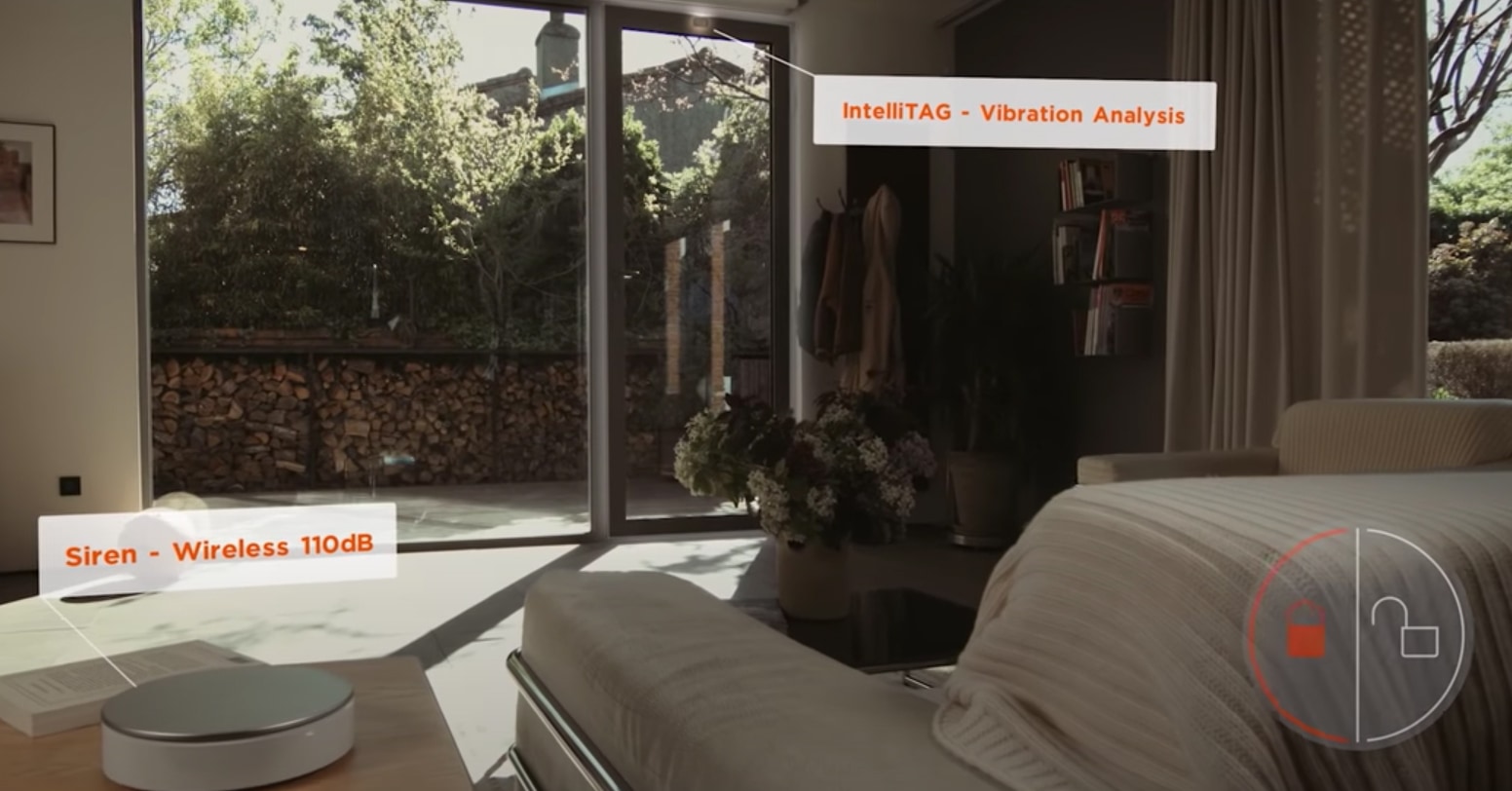 screengrab from a youtube video of an interior home scene with graphic overlays saying "Siren - Wireless 110dB" and "IntelliTAG - Vibration Analysis"