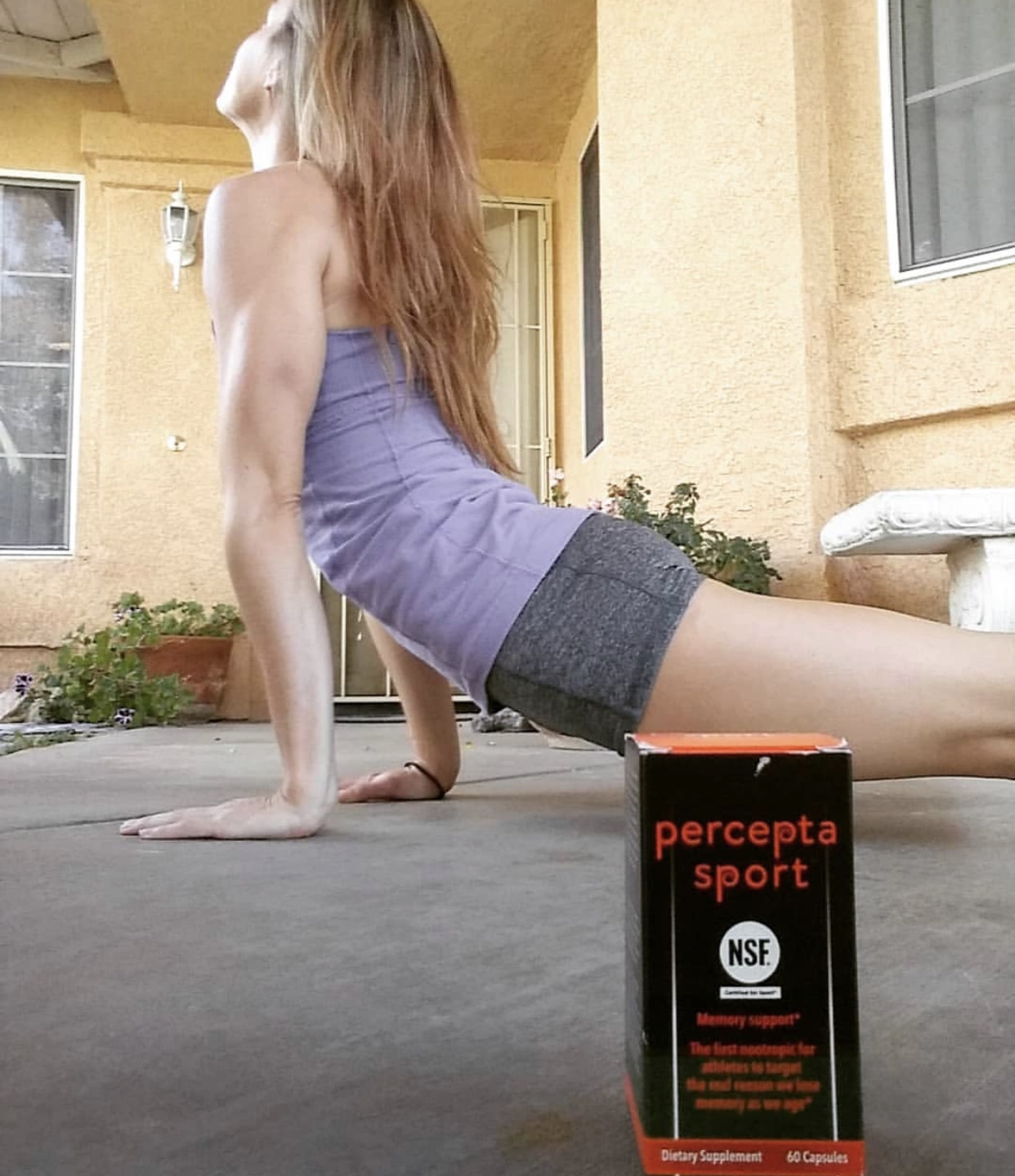 Woman performing yoga pose with a box of percepta sport in the foreground