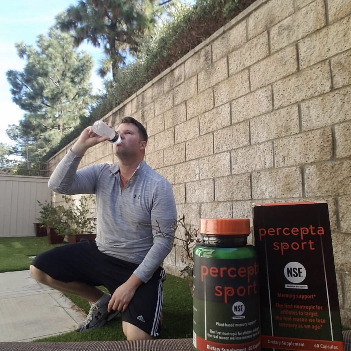 Man drinking water with boxes of percepta sport in front of him