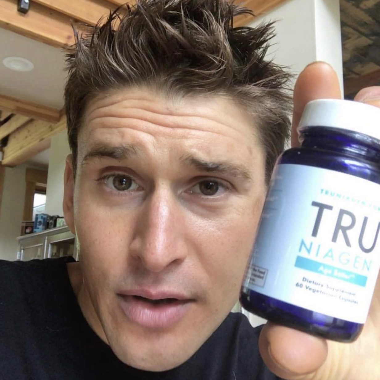 Male influencer holding bottle of nutraceutical product next to his face