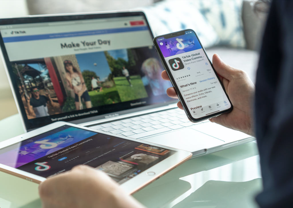 Image of person working on laptop, phone, and tablet with TikTok app open