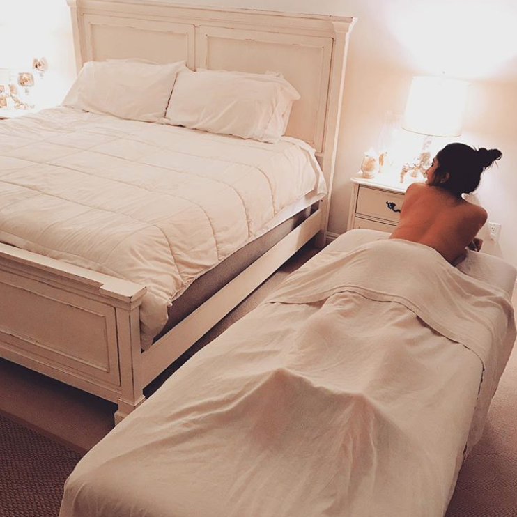 Woman in bedroom lying on massage table Woman lying on massage table and smiling, with bed and other bedroom furniture around her