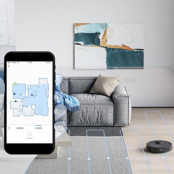 App displaying a house's layout for household electronics products Living room couch with a robot vacuum next to it, with an overlay photo of a cell phone showing a house's blueprint in an app